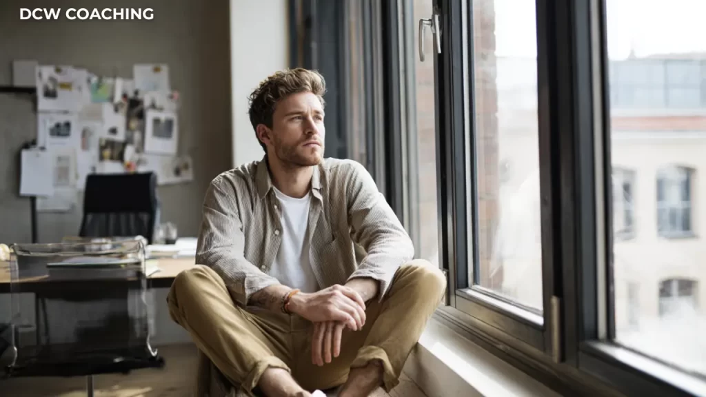 Small business owner sitting by a window, reflecting on business decisions